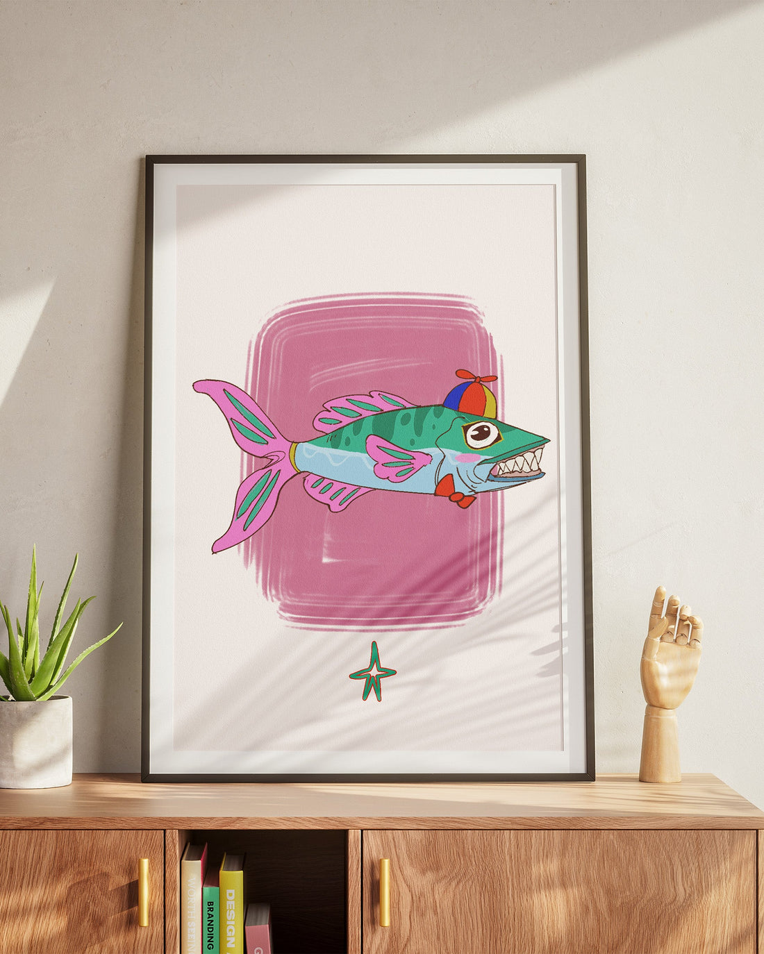 Framed artwork of a colorful fish on a wall above a wooden cabinet.