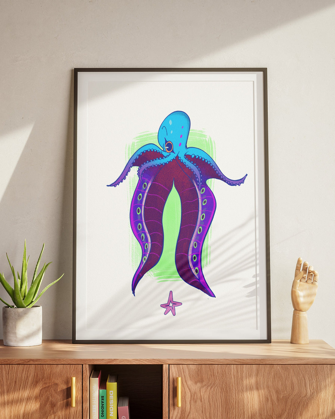 Framed artwork of a colorful octopus on a wall above a wooden cabinet.