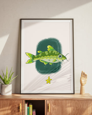 Framed artwork of a green fish on a white background, displayed on a wooden cabinet.