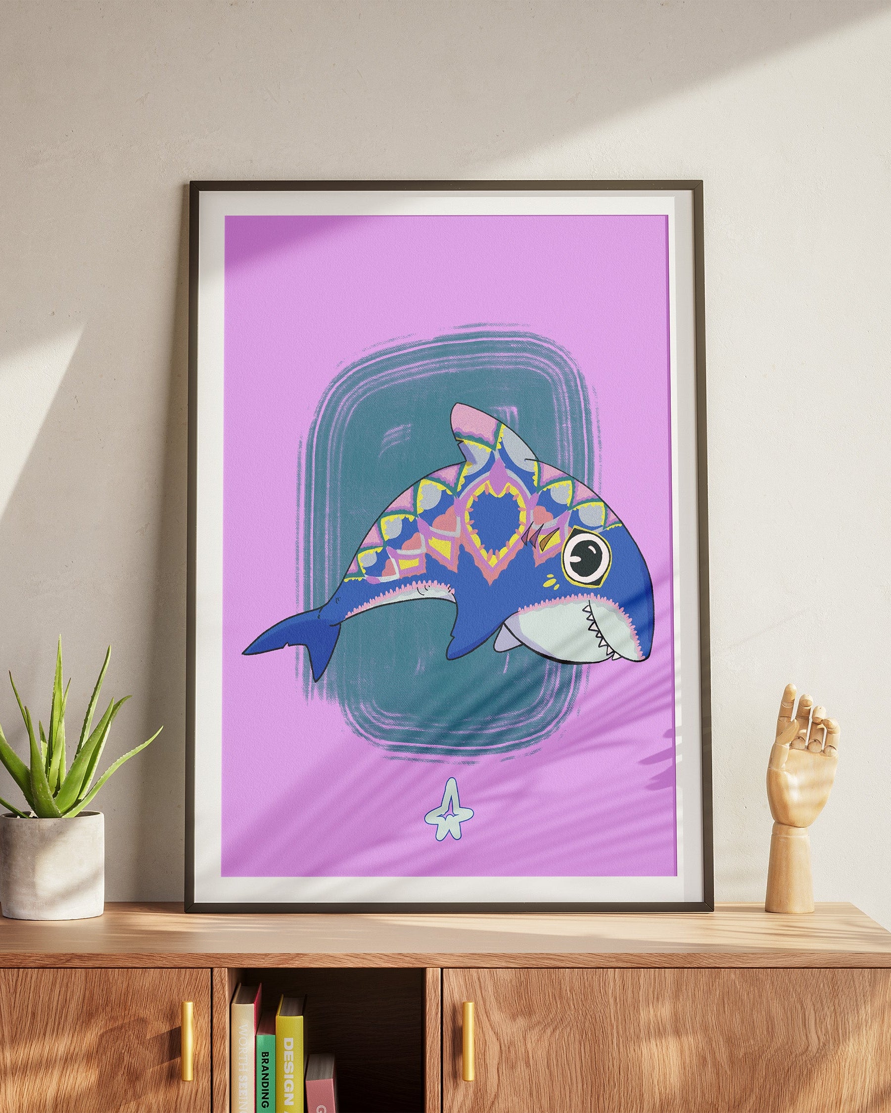 Framed artwork of a colorful fish on a purple background, displayed on a wooden cabinet.
