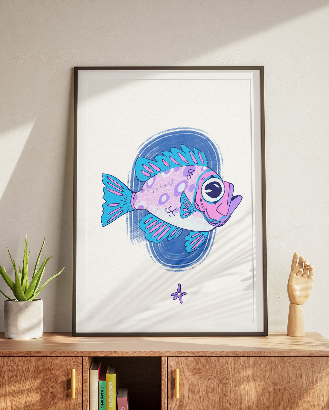 Framed artwork of a colorful fish on a wall above a wooden cabinet.
