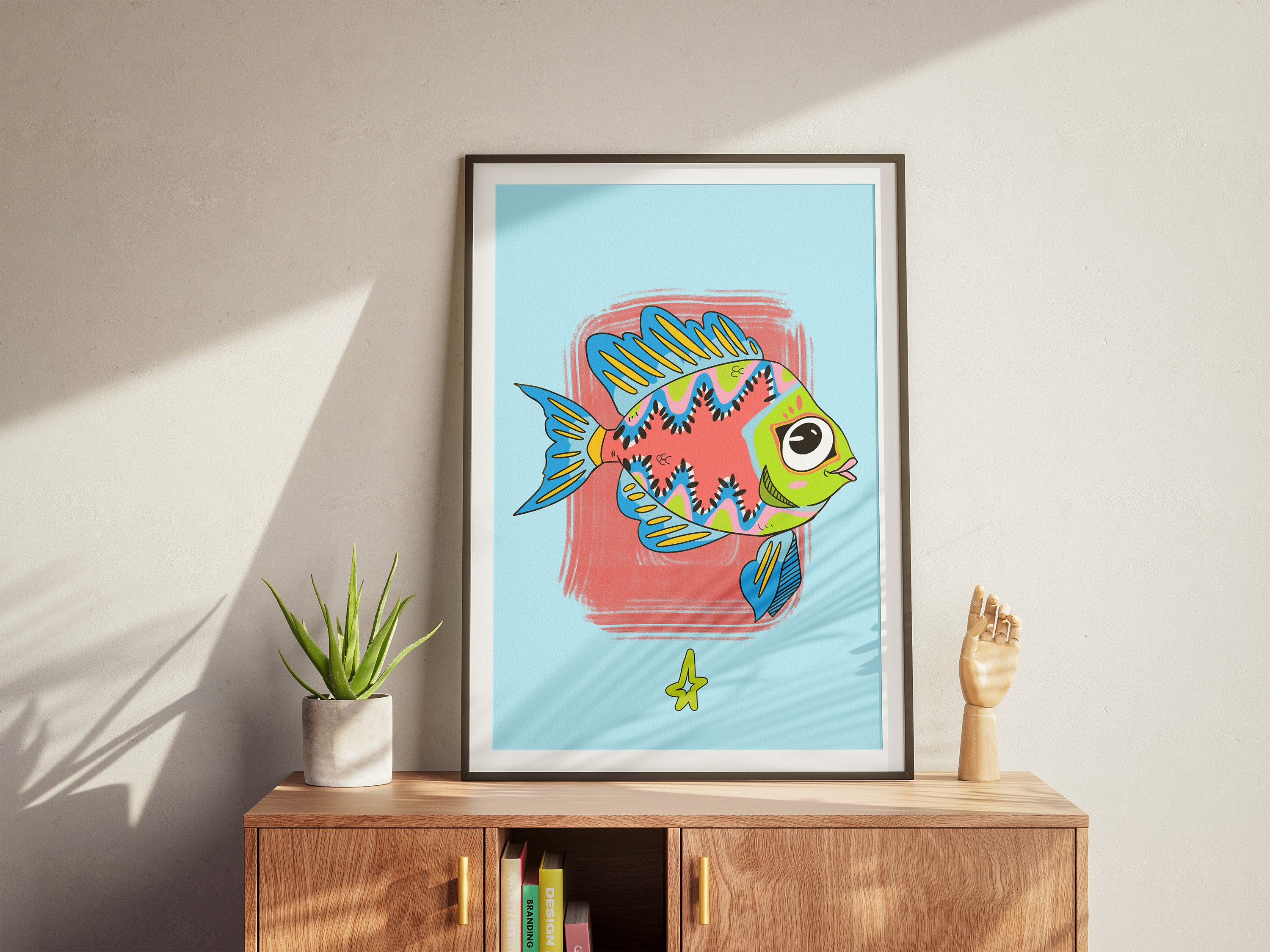 Framed artwork of a colorful fish on a wall above a wooden cabinet.