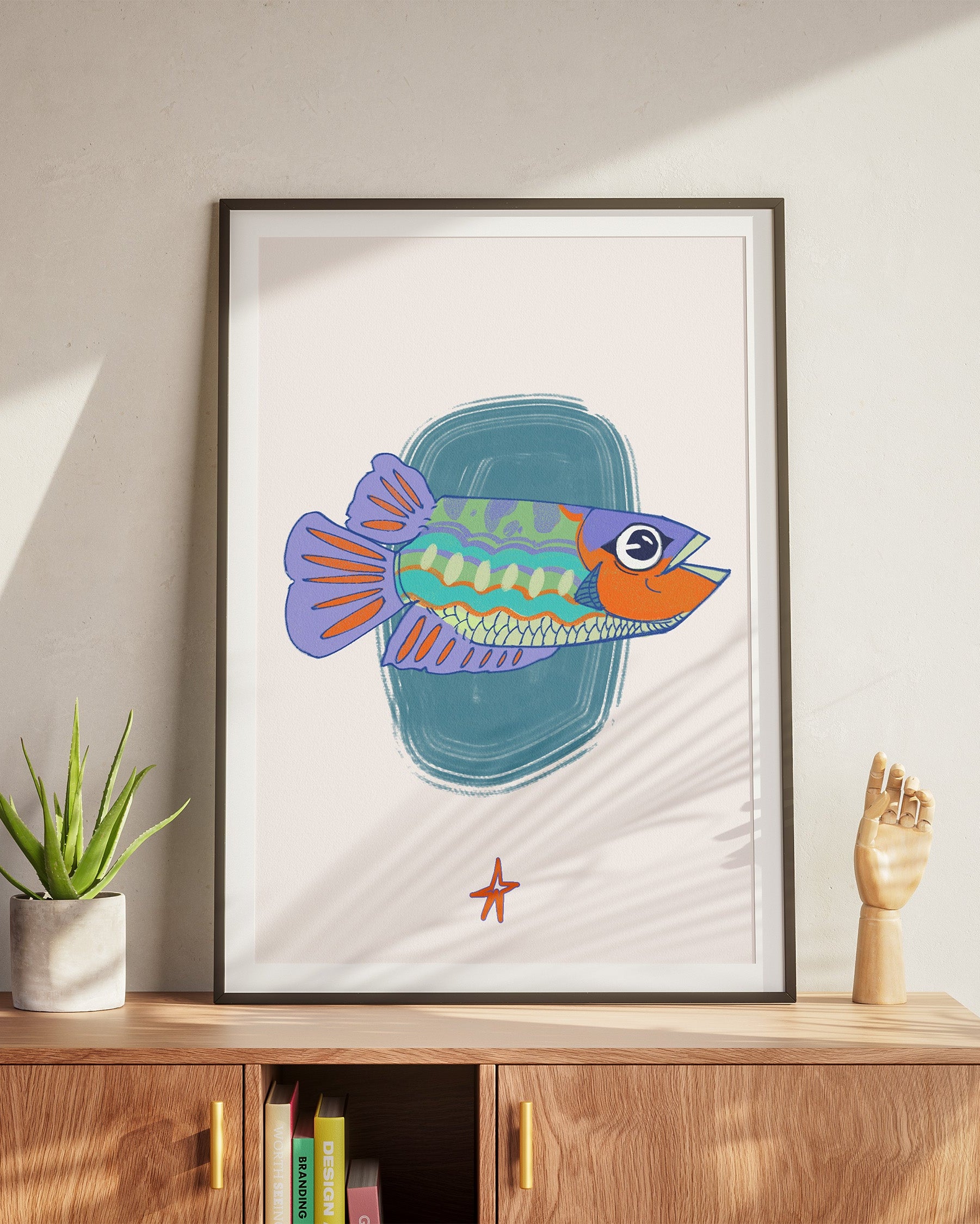 Framed illustration of a colorful fish on a wall above a wooden cabinet.